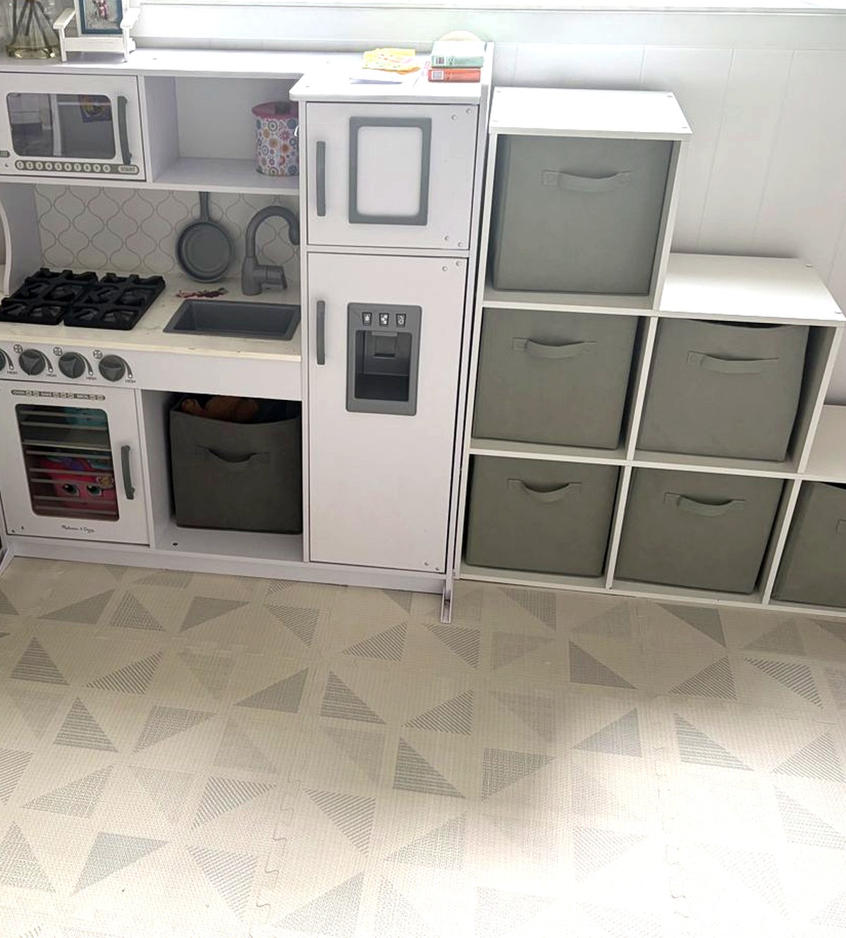 White play kitchen and gray storage bins in a tidy play corner